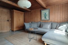 Wohnzimmer mit grauem Sofa und Holzschrank