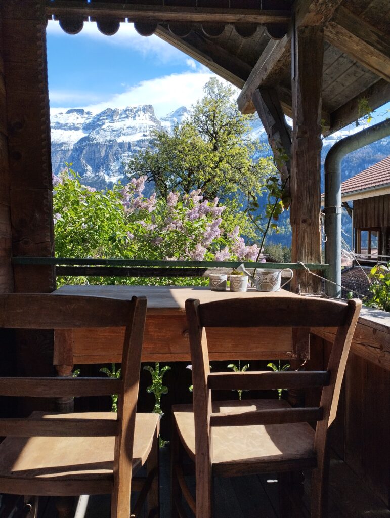 Holztisch mit Holzstühlen auf der Laube des Ferienhauses Schwanderbärgli