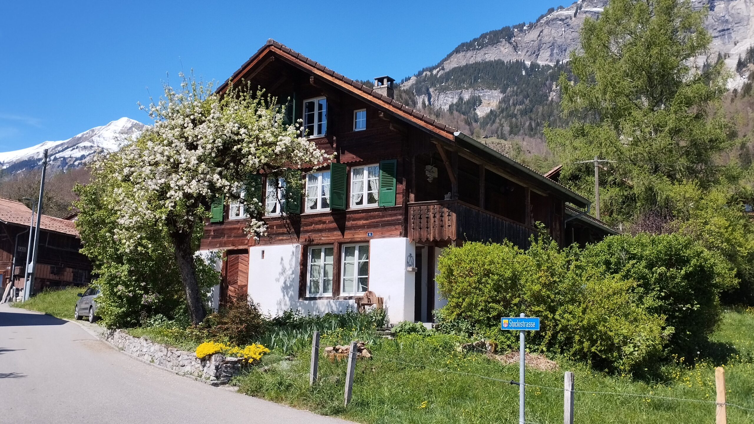 Ferienhaus Schwanderbärgli von aussen mit Blick auf den Parkplatz und das Strassenschild